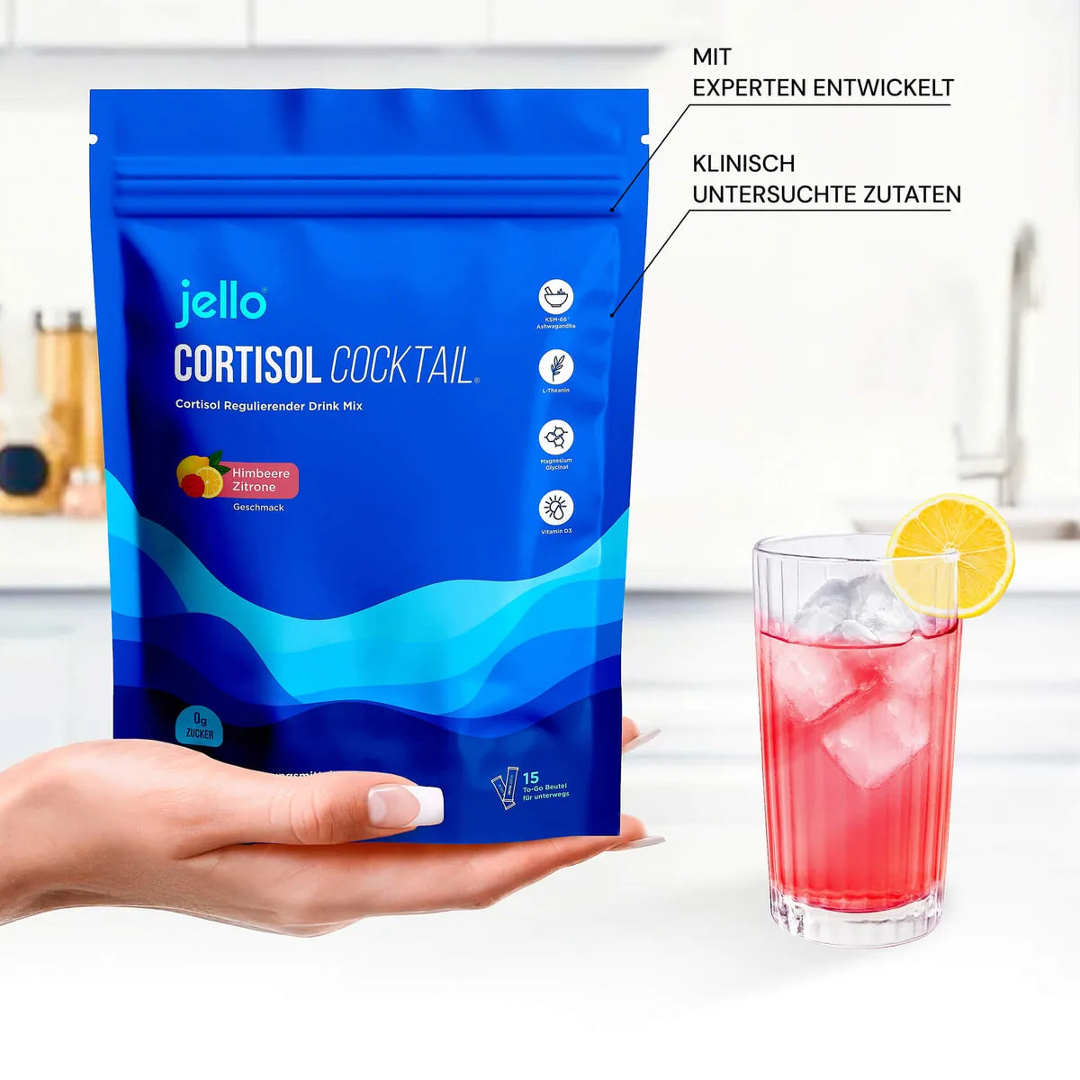 Hand hält den Jello Cortisol Cocktail Beutel, daneben ein Glas mit Zitronenscheibe.